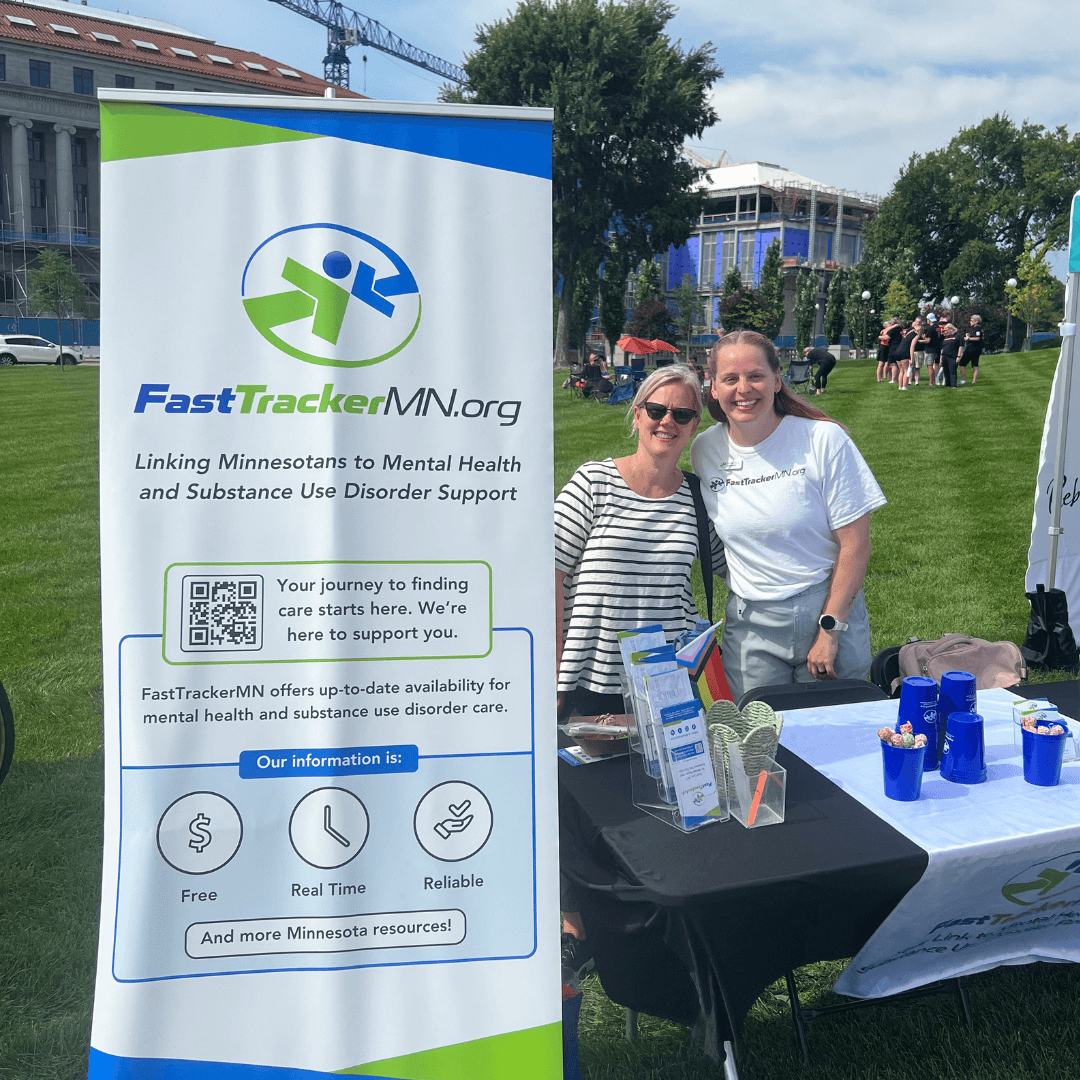 The FastTrackerMN booth with employees standing at it.